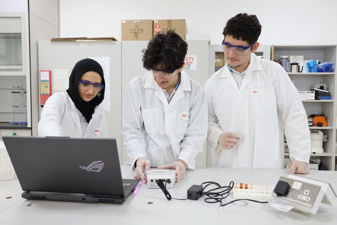 ANPS students in lab coats and safety goggles working in the science and STEM laboratory