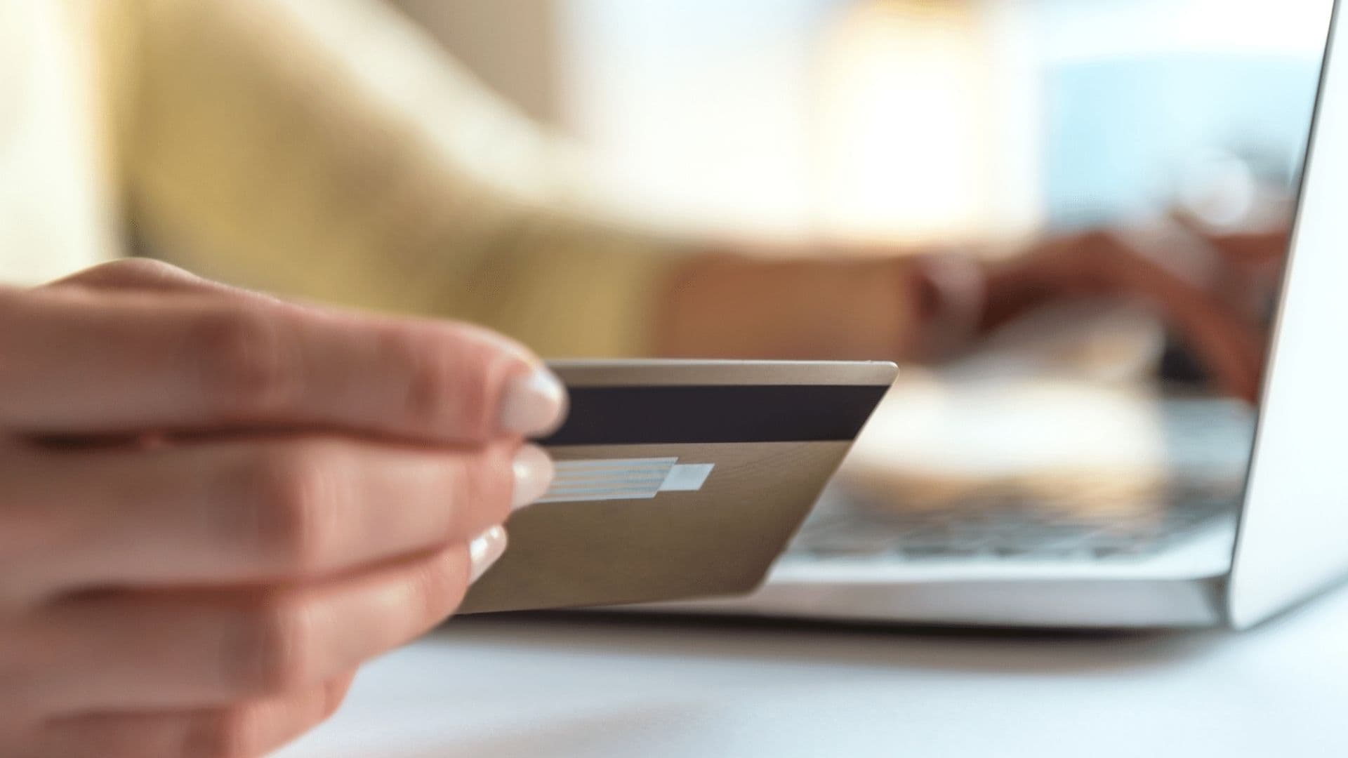 A parent holding a bank card at a laptop, making a hassle-free online tuition payment